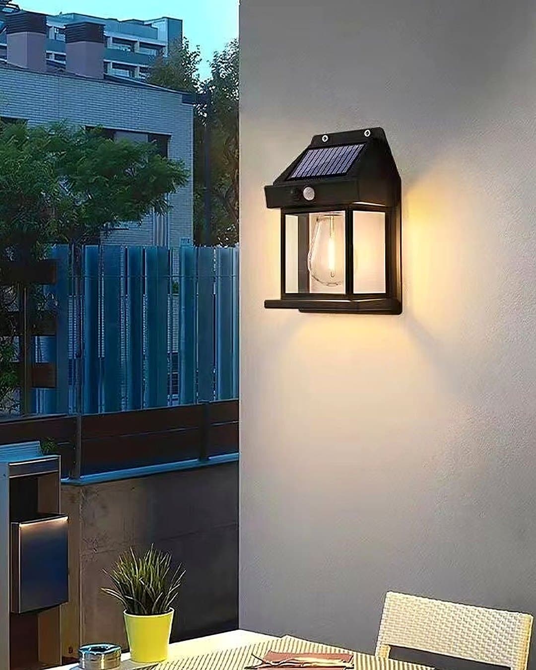 La lampe solaire allumée sur le mur d'un balcon, au-dessus d'une petite table
